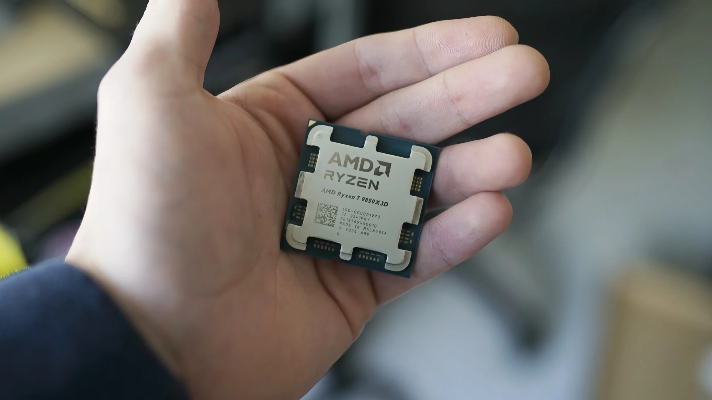 A hand holding the Ryzen 7 9850X3D.